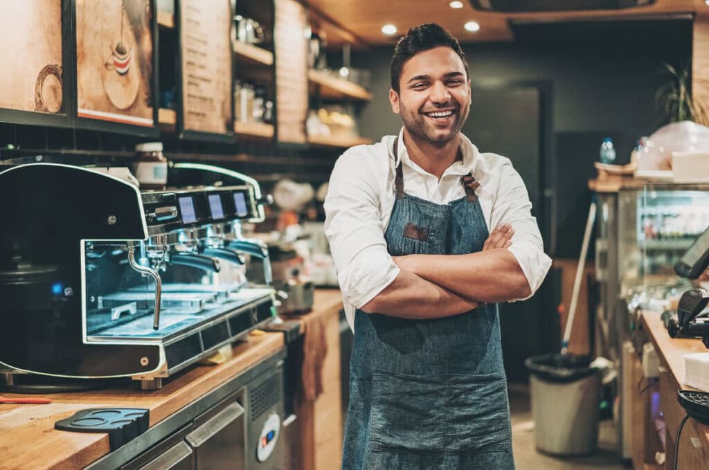 Smiling barista in cafe, arms crossed