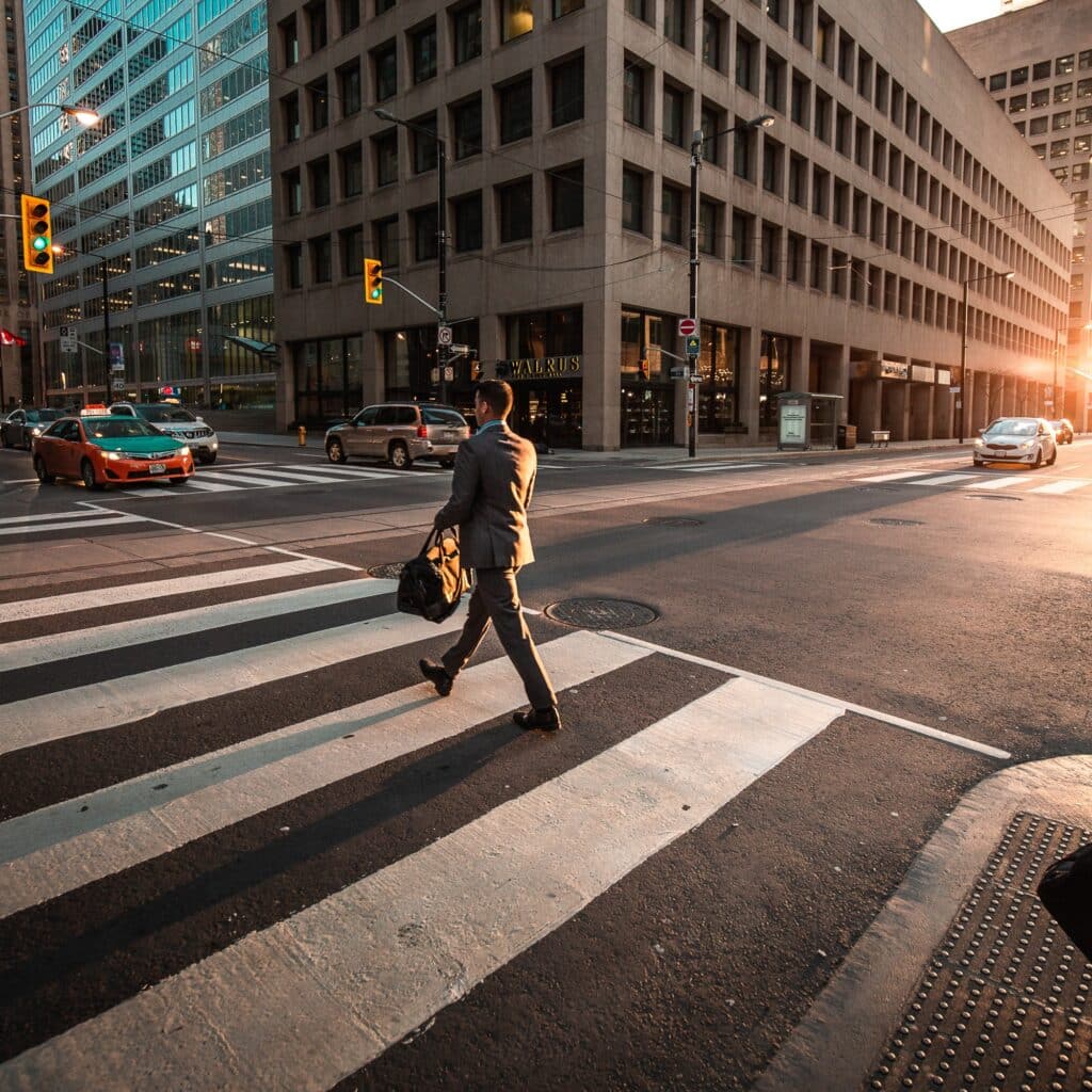 Office worker crossing street on their way to the office again after working remotely due to the Covid-19 pandemic.