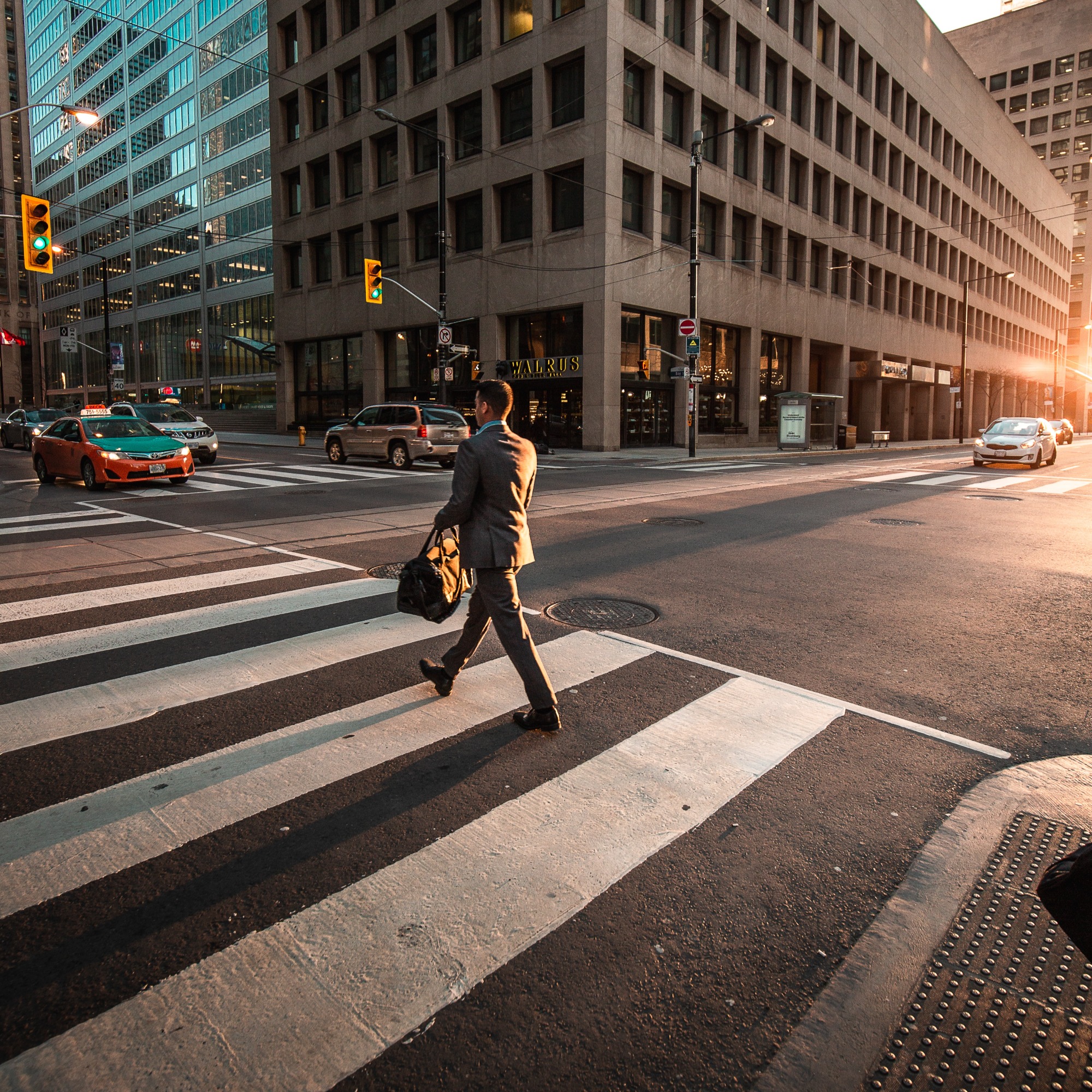 Office worker crossing street on their way to the office again after working remotely due to the Covid-19 pandemic.
